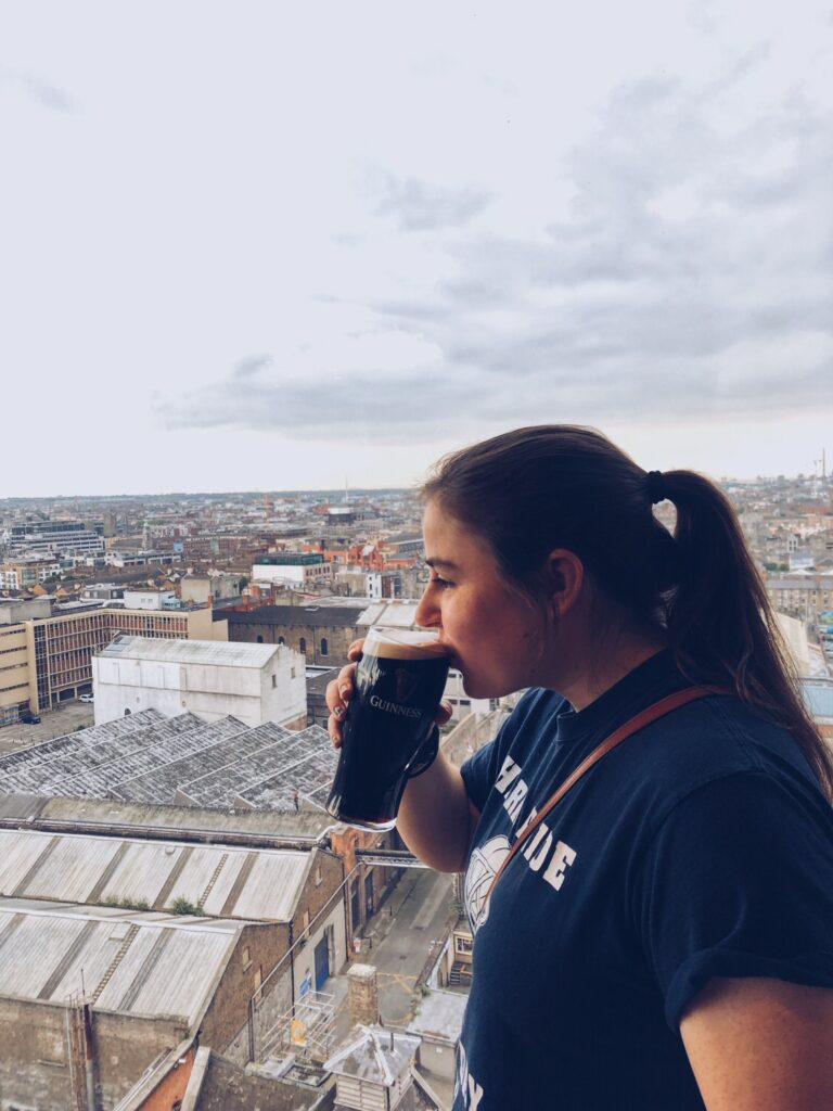 A woman enjoying a pint of Guinness with a view of the Dublin cityscape from the Guinness Storehouse.