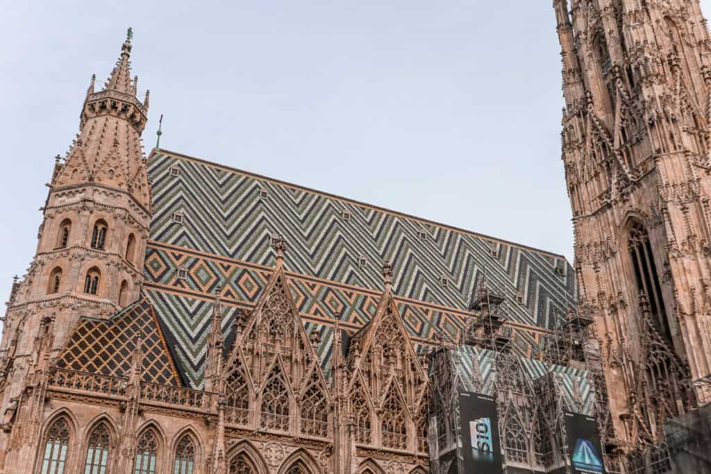 St. Stephen's Cathedral in Vienna, featuring its patterned, multi-colored tiled roof and Gothic architecture, with a clear view of its spire and flying buttresses.