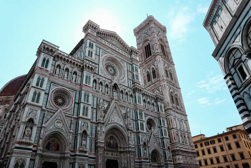 The Florence Cathedral, Santa Maria del Fiore, with its ornate marble facade in white, green, and pink, and its towering red-tiled dome and Giotto's bell tower.