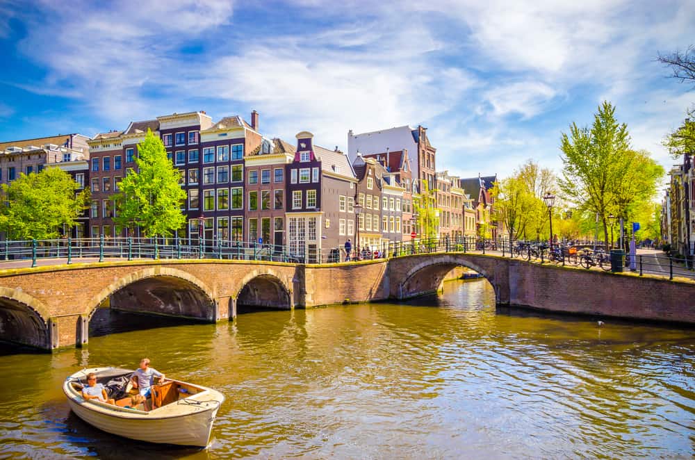 A leisurely boat ride on Amsterdam's scenic canals, showcasing the historic architecture and bridges under a clear blue sky